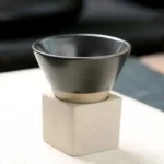 Stainless steel bowl on a white cube stand, used for science experiments or educational demonstrations.