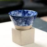 Blue and white marbled ceramic bowl on a beige stand.