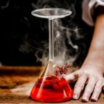 Laboratory glassware with red liquid and steam, demonstrating a science experiment setup.