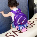 Adorable purple space rocket backpack with pink fins for children, perfect for school or travel, featuring a fun rocket design and adjustable straps.