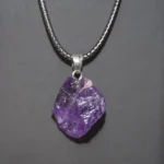Amethyst crystal pendant necklace with a silver chain, showcasing a raw purple gemstone. Perfect for science-inspired jewelry and educational gift ideas.