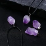Handcrafted amethyst crystal necklace and earrings with raw purple stones on black background.