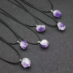 Set of five amethyst crystal pendant necklaces with black cords, showcasing natural purple gemstone jewelry on a dark background.