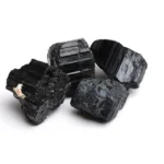 Black Tourmaline crystal stones with a rough, natural appearance, showcasing their striated texture and deep black color.