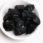 Black Tourmaline crystals in a white bowl, used for energy cleansing, protection, and grounding. Perfect for educational displays or as a natural science decor piece.