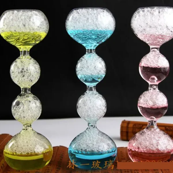 Vibrant glass hourglasses filled with bubbling colored liquids in yellow, blue, and pink, displayed against a black background.