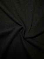 Dark black textile material with a prominent twist in the center, showcasing its smooth texture and subtle sheen.
