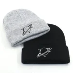 Space planet embroidered beanie hats, one in gray and one in black, featuring a minimalist planet with rings design. Perfect for science enthusiasts and educational settings.