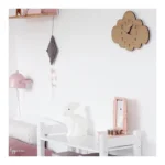 Cloud-shaped wooden wall clock with black numbers and hands, mounted on a white wall in a child's room.