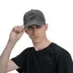 Young man wearing a SpaceX cap with astronaut logo, adjusting the cap with his hand, against a plain white background.