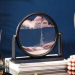 Intricate mountain landscape sand art in a circular frame, showcasing layered colored sand creating a scenic mountain view, perfect for educational and decorative purposes.