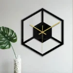 Stylish black and gold geometric wall clock with a 3D cube design, mounted on a white wall, adding a contemporary touch to home decor.