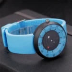 Modern digital watch featuring a blue strap and a distinctive circular dial with black and red accents, ideal for science-themed decor and educational purposes.