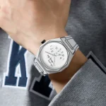 Close-up of a modern white wristwatch with a distinctive dial featuring black numbers and hands, worn on a person's wrist.
