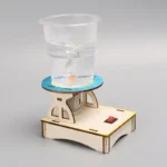Small water cycle model demonstrating evaporation, condensation, and precipitation with a clear container, wooden base, and colorful platform for educational purposes.