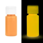Small yellow glow-in-the-dark paint bottle illuminated in the dark, showcasing its luminous properties for science experiments and educational projects.