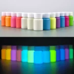Vibrant bottles of glow-in-the-dark paint arranged in a row, showcasing their bright colors under normal and UV light.