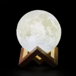 Realistic moon lamp night light resembling the lunar surface, mounted on a wooden stand, perfect for space-themed decor and educational purposes.