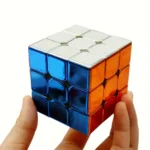 Hand holding a solved 3x3 Rubik's Cube with blue, orange, and white sides, showcasing a classic twisty puzzle for brain training and entertainment.