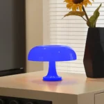 Bright blue mushroom-shaped LED night light on a wooden surface, illuminating a cozy indoor space with a modern aesthetic.