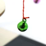 Close-up of a green liquid drop suspended by a red thread, demonstrating magnetic properties and fluid dynamics.