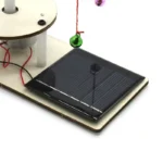 Solar power science kit demonstrating solar energy conversion with a small solar panel, a hanging bell, and electrical components for educational experiments.