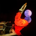 Detailed model of a space shuttle launching with a fiery exhaust, accompanied by a realistic moon replica reflecting on a glossy surface. Perfect for science decor and educational displays.