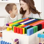 Happy mother and son playing with colorful educational dominoes and science toys on a white table, fostering learning and fun.