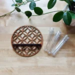 Decorative wooden coaster with intricate geometric pattern accompanied by three clear glass test tubes on a light wooden surface, ideal for science-themed decor or educational displays.