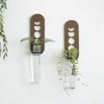 Stylish wall planters featuring metal frames with circular cutouts, holding glass vases with lush green plants.