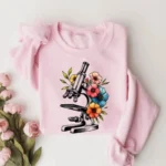 Vérifiez cette illustration de microscope entouré de fleurs colorées, parfaite pour un t-shirt original et scientifique.