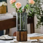 Stylish glass vase with pink roses on a wooden table, perfect for home decor and floral arrangements.