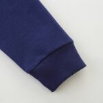 An image showcasing a close-up of a navy blue sweatshirt sleeve with a ribbed cuff, highlighting the fabric texture and stitching detail.