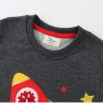 Rocket-themed sweatshirt with colorful patches and star designs, perfect for science enthusiasts and educational settings.