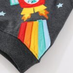 Colorful rocket embroidery patch on dark fabric, featuring rainbow tail and star details, perfect for science-themed decor or educational toys.
