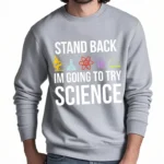 Une veste à capuche noire avec le texte "Stand Back, I'm Going to Try Science" et des icônes de laboratoire colorées, idéale pour les amateurs de science et de décoration scientifique.