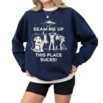 Navy blue sweatshirt featuring a retro sci-fi design with an alien spaceship and astronauts, with the humorous phrase "Beam Me Up This Place Sucks!" for science and space enthusiasts.