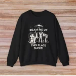 Black sweatshirt featuring a humorous sci-fi design with a girl, aliens, and spaceship, with the text "BEAM ME UP THIS PLACE SUCKS!" for science and space enthusiasts.