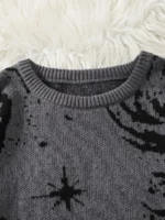 Gros plan sur un pull en laine gris foncé avec motif d'étoile noir, posé sur un fond en peluche blanche, idéal pour la décoration scientifique et la mode.