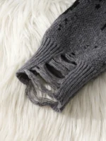 Worn gray knitted sweater with distressed holes on a white furry background.