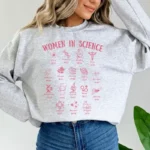 Sweatshirt gris avec illustrations de femmes en science et leurs noms, célébrant l'apport féminin dans la recherche et la découverte scientifique.